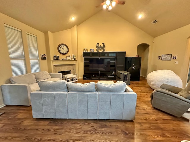 living room featuring hardwood / wood-style flooring, high vaulted ceiling, and a tile fireplace