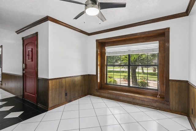 unfurnished room featuring ceiling fan, crown molding, and light tile patterned flooring