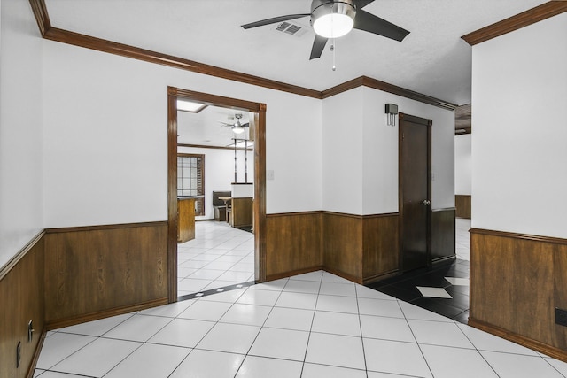 empty room with ceiling fan, ornamental molding, and light tile patterned flooring