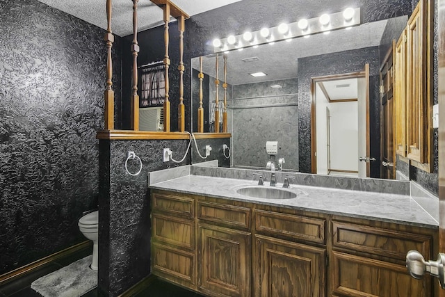 bathroom featuring a textured ceiling, vanity, and toilet