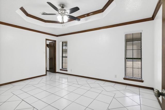 empty room with light tile patterned floors, a tray ceiling, ceiling fan, and crown molding