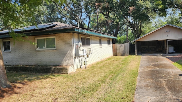 view of home's exterior featuring a lawn, solar panels, a garage, and an outbuilding