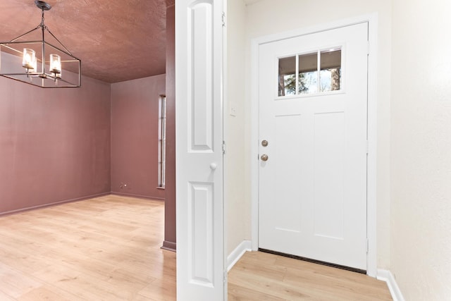 foyer entrance featuring light hardwood / wood-style flooring and an inviting chandelier