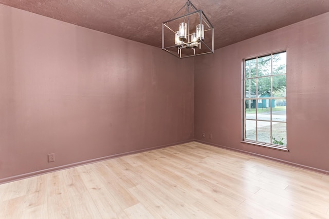 unfurnished room featuring light hardwood / wood-style floors, an inviting chandelier, and plenty of natural light