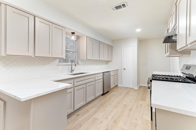 kitchen featuring dishwasher, sink, gas range, light wood-type flooring, and light stone counters