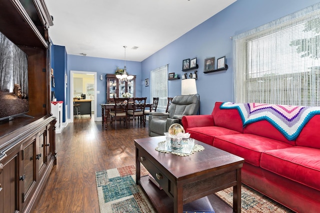 living room with dark wood-type flooring and a notable chandelier