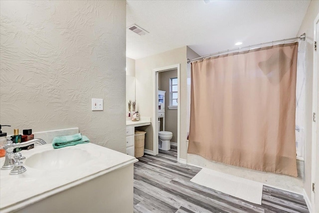 3821 Suncrest Dr, Groves, TX 77619 - full bath with wood finished floors, vanity, a textured wall, and shower / bath combination with curtain
