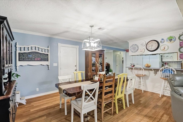 3821 Suncrest Dr, Groves, TX 77619 - dining area featuring light wood-type flooring, a chandelier, a textured ceiling, and crown molding