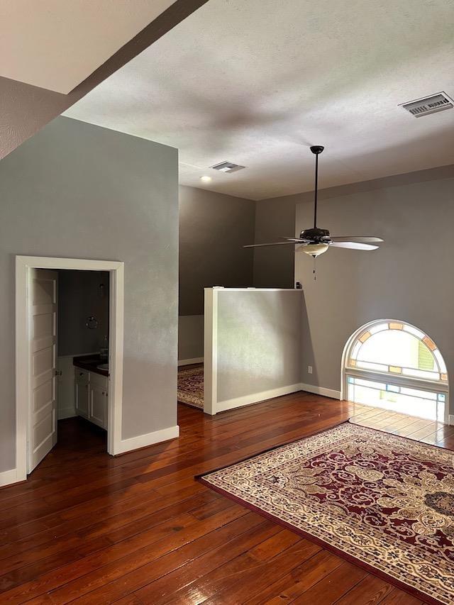 interior space with ceiling fan, ensuite bathroom, and dark wood-type flooring