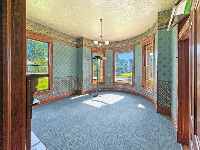 interior space featuring a notable chandelier, carpet floors, and a textured ceiling