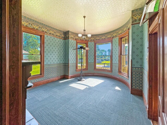 interior space featuring a notable chandelier, carpet floors, and a textured ceiling