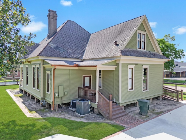 back of house featuring cooling unit and a lawn