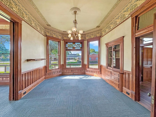 carpeted spare room featuring an inviting chandelier