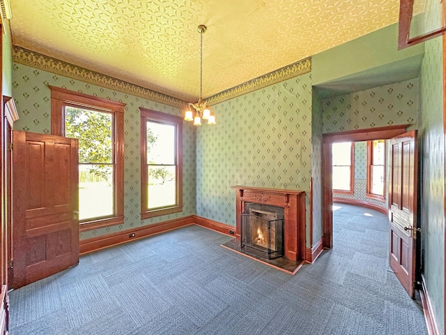 unfurnished living room featuring carpet flooring, a textured ceiling, and a chandelier