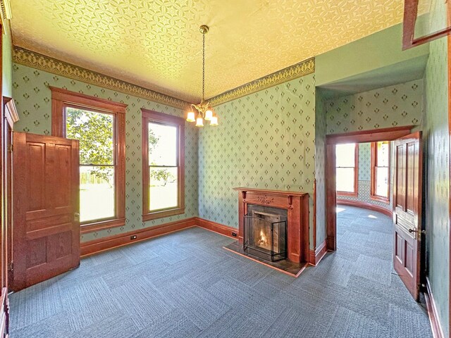 unfurnished living room featuring carpet flooring, a textured ceiling, and a chandelier