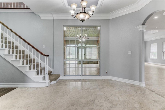 foyer entrance with a notable chandelier, ornamental molding, and ornate columns