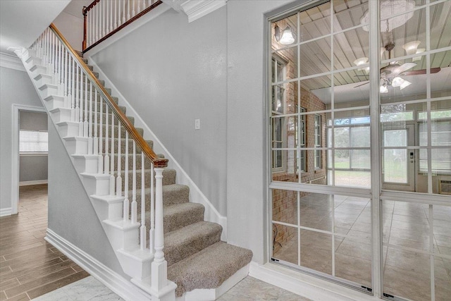 staircase with ceiling fan and ornamental molding