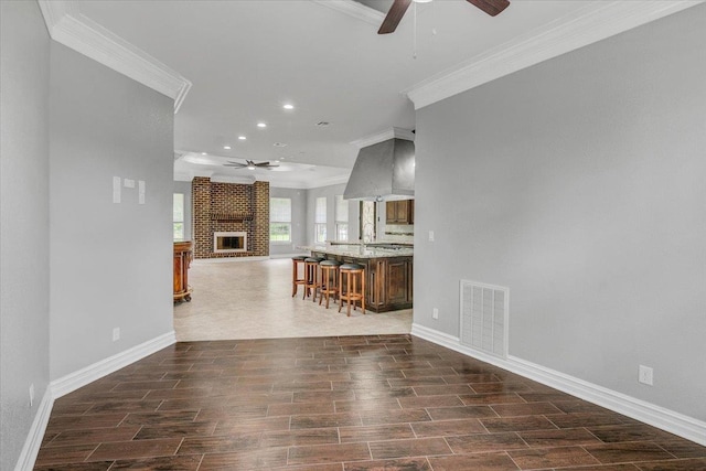 unfurnished living room with ceiling fan, a fireplace, and ornamental molding