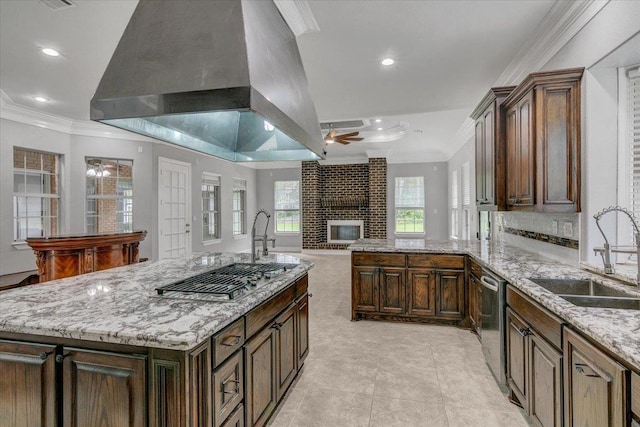 kitchen featuring light stone countertops, stainless steel appliances, extractor fan, sink, and a fireplace