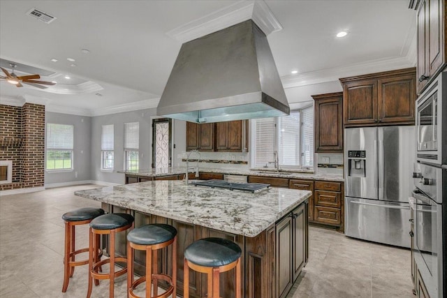 kitchen featuring a large island, sink, stainless steel appliances, light stone counters, and island exhaust hood