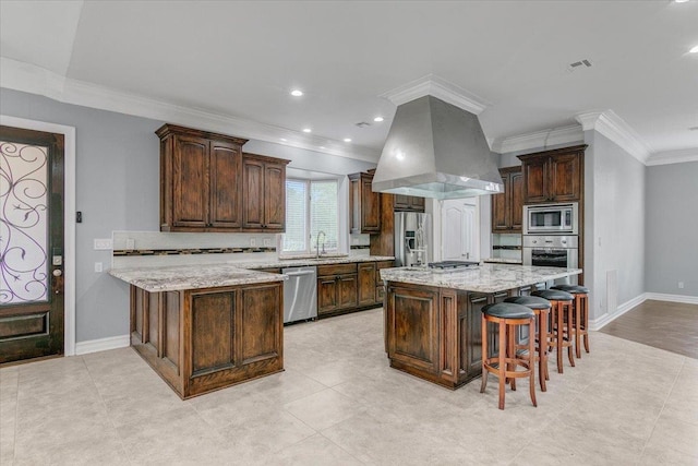 kitchen with a kitchen breakfast bar, dark brown cabinetry, stainless steel appliances, island range hood, and a kitchen island