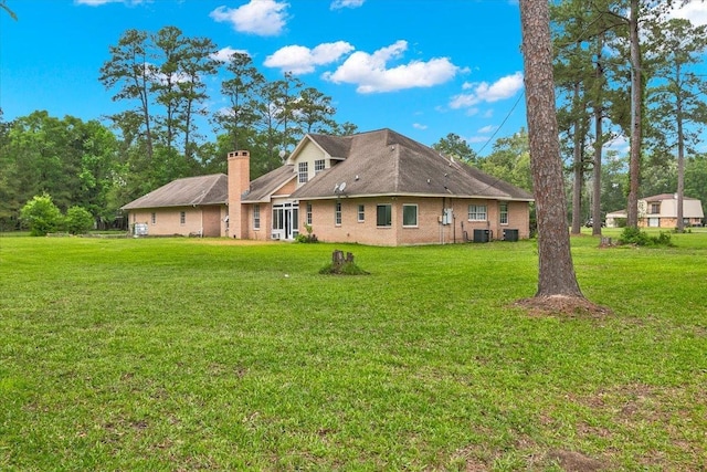 rear view of property featuring a lawn and central AC unit