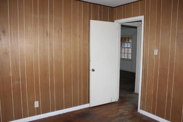 unfurnished room featuring dark wood-style floors and wooden walls