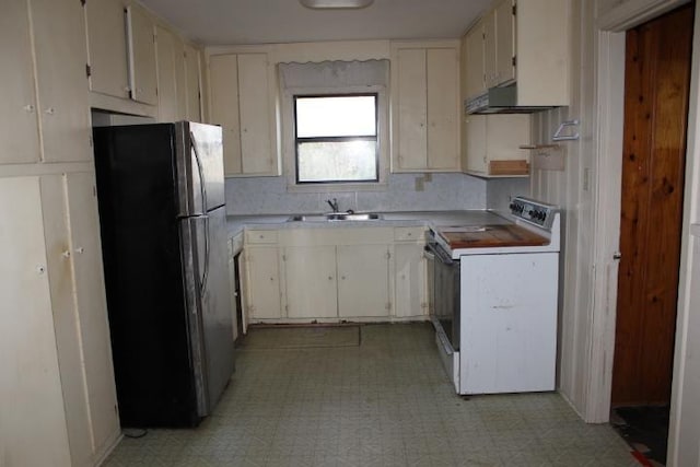 kitchen with a sink, light countertops, freestanding refrigerator, light floors, and white range with electric cooktop