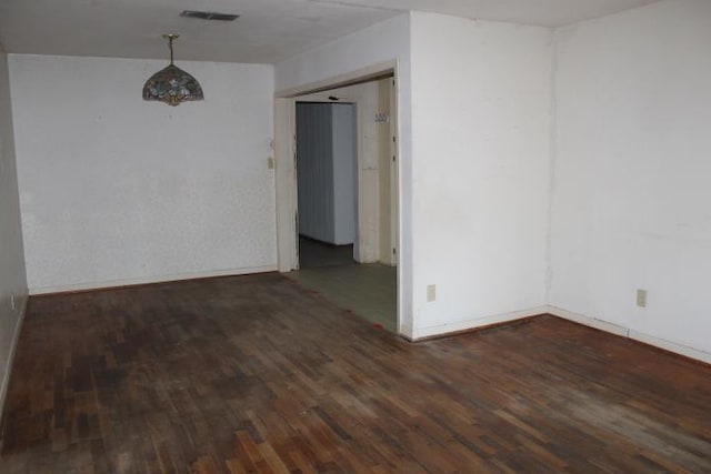 unfurnished room with baseboards, visible vents, and wood finished floors