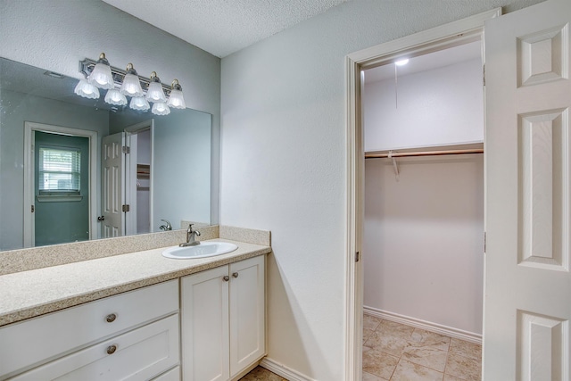 246 Pinevale Way, Sour Lake, TX 77659 - bathroom featuring vanity, a walk in closet, a textured ceiling, baseboards, and tile patterned floors