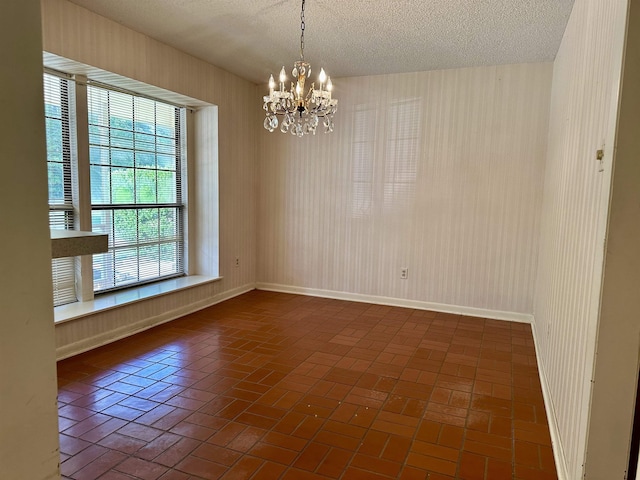 empty room with a chandelier and a textured ceiling