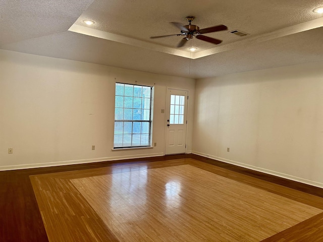 unfurnished room with hardwood / wood-style flooring, ceiling fan, a raised ceiling, and a textured ceiling