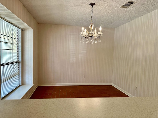 unfurnished dining area with a textured ceiling and a notable chandelier