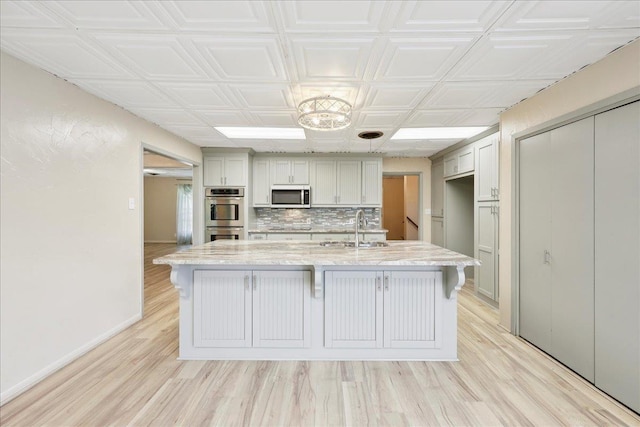 2701 Mcbride Dr, Port Neches, TX 77651 - kitchen with stainless steel appliances, a breakfast bar, light wood-style floors, decorative backsplash, and light stone countertops