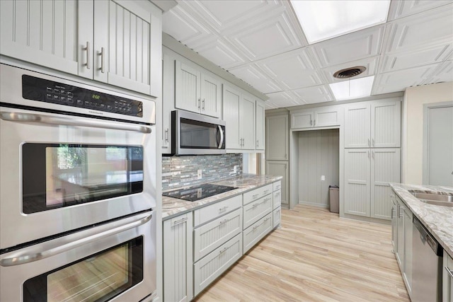 2701 Mcbride Dr, Port Neches, TX 77651 - kitchen featuring appliances with stainless steel finishes, decorative backsplash, light wood-style floors, light stone counters, and an ornate ceiling