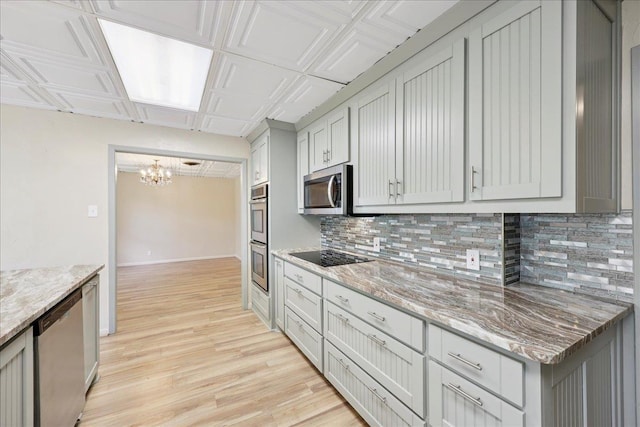 2701 Mcbride Dr, Port Neches, TX 77651 - kitchen with appliances with stainless steel finishes, tasteful backsplash, a chandelier, light wood-style floors, and light stone counters