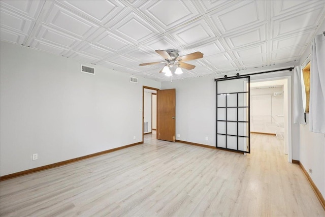 2701 Mcbride Dr, Port Neches, TX 77651 - empty room featuring a ceiling fan, light wood-style flooring, an ornate ceiling, and a barn door
