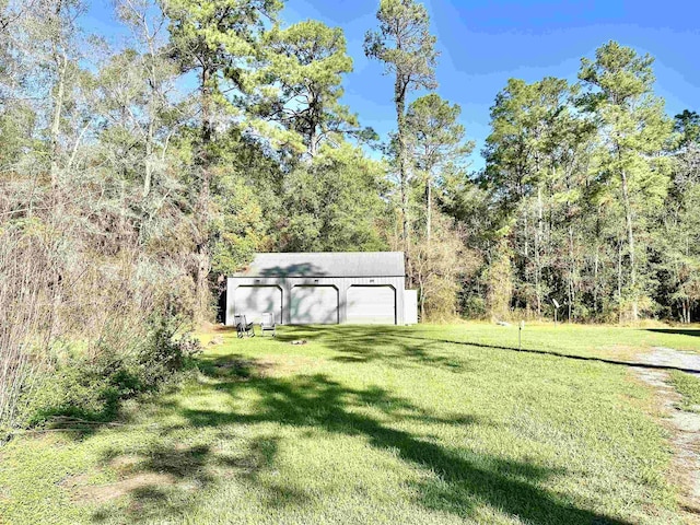 view of yard with an outbuilding, a forest view, and a detached garage