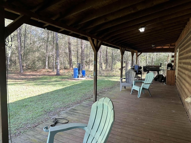 wooden terrace featuring a yard, a view of trees, and grilling area