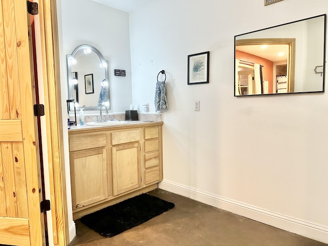 bathroom with baseboards, vanity, and concrete flooring