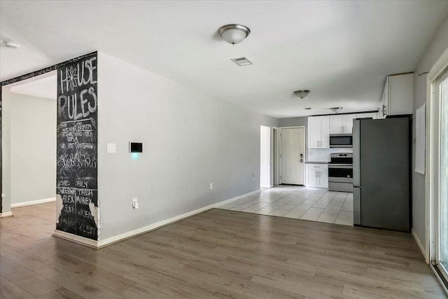 kitchen with white cabinets, stainless steel appliances, tasteful backsplash, and light hardwood / wood-style floors