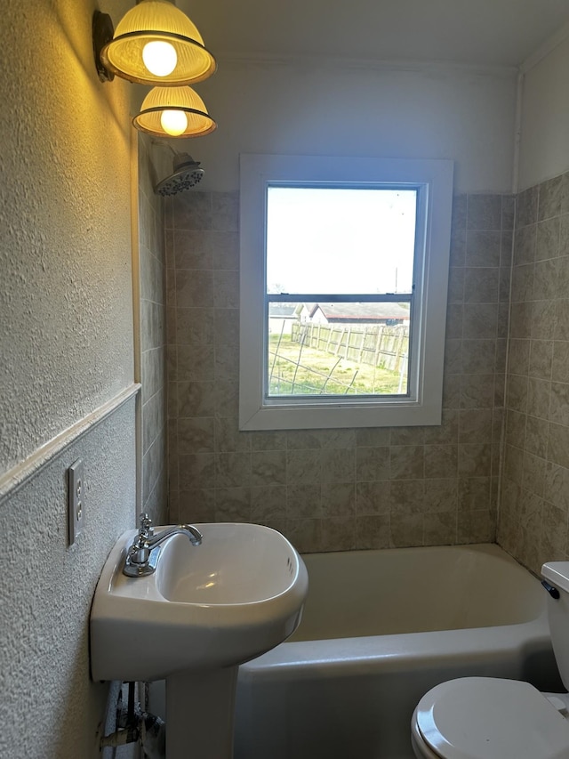 full bathroom featuring toilet, a sink, and a textured wall