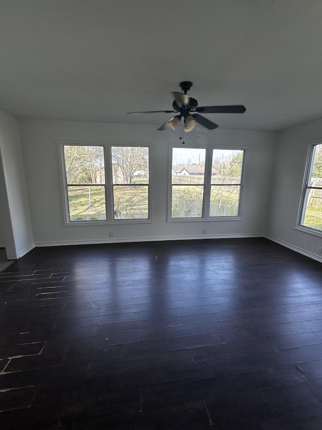 empty room featuring dark wood-style flooring, ceiling fan, and baseboards