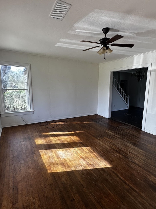 unfurnished room featuring a textured ceiling, dark wood-style flooring, visible vents, a ceiling fan, and stairs