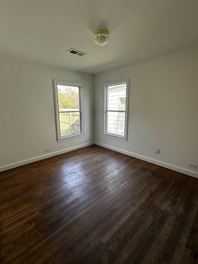 spare room with visible vents, dark wood finished floors, and baseboards