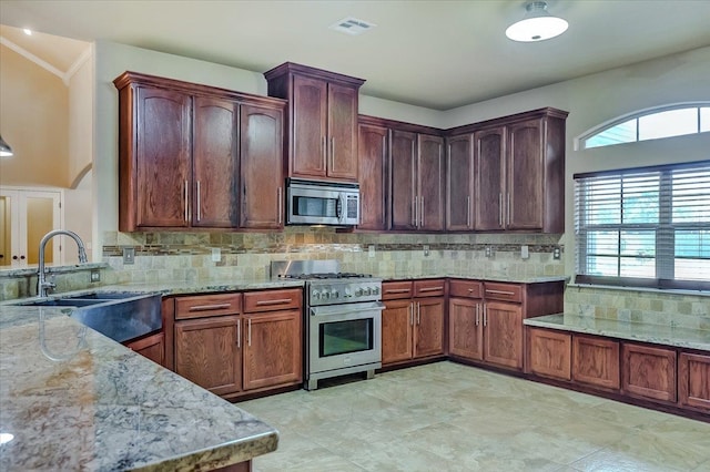 kitchen with decorative backsplash, sink, light stone countertops, and stainless steel appliances