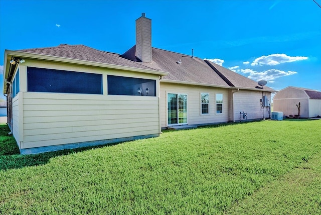 rear view of property featuring central AC and a lawn