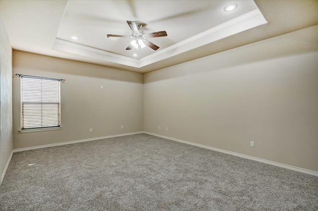 carpeted empty room featuring ceiling fan, a raised ceiling, and crown molding