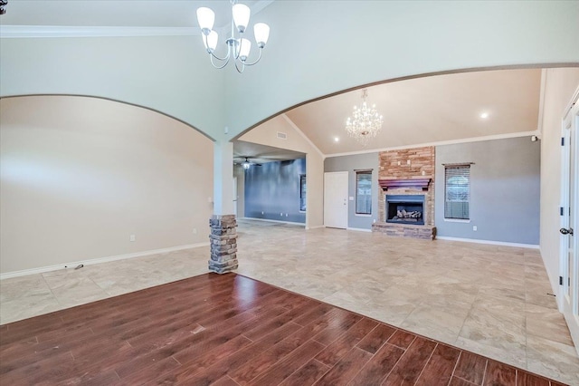 unfurnished living room with ceiling fan with notable chandelier, crown molding, a fireplace, and vaulted ceiling