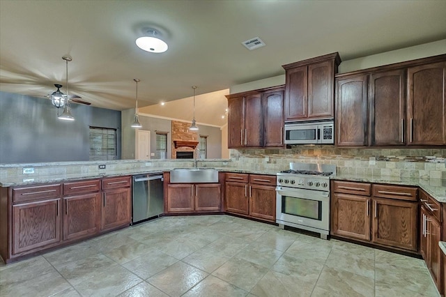 kitchen featuring decorative light fixtures, kitchen peninsula, sink, and appliances with stainless steel finishes